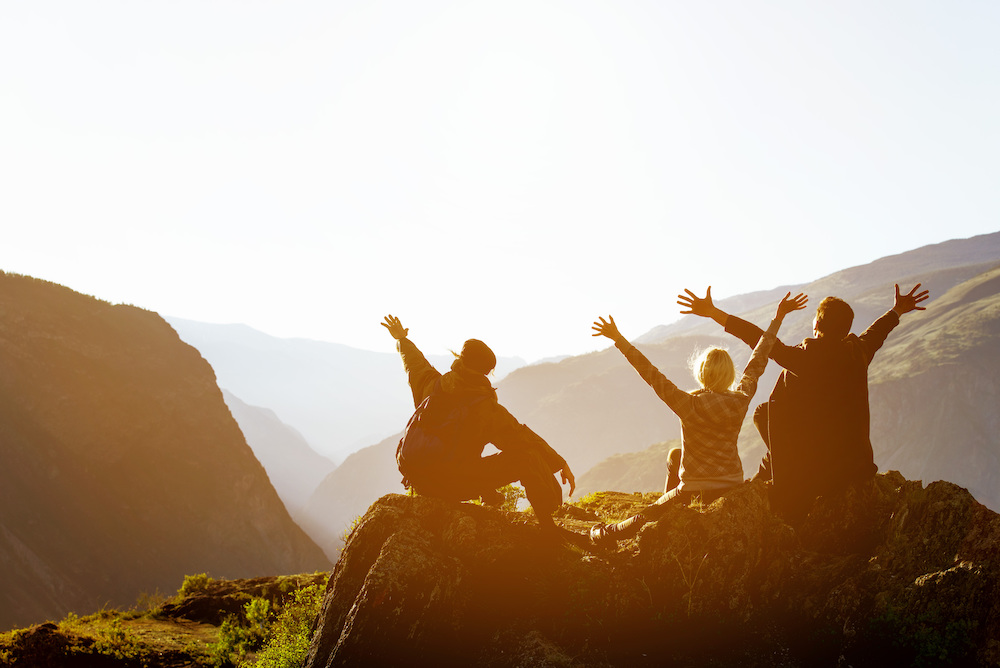 A group of people sit at the top of a mountain after hiking.