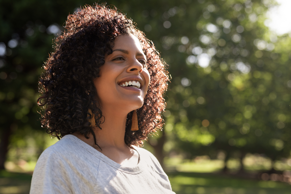 A woman smiles while walking in a park.