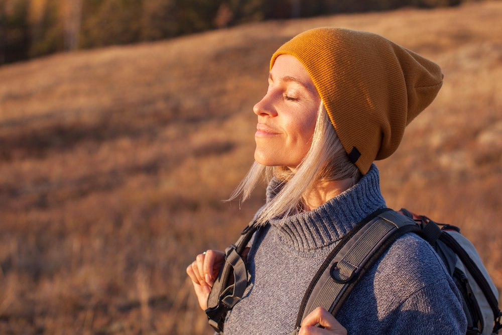 A woman stops to meditate while hiking.