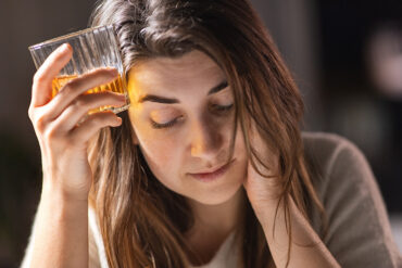 A woman self-medicates with alcohol.